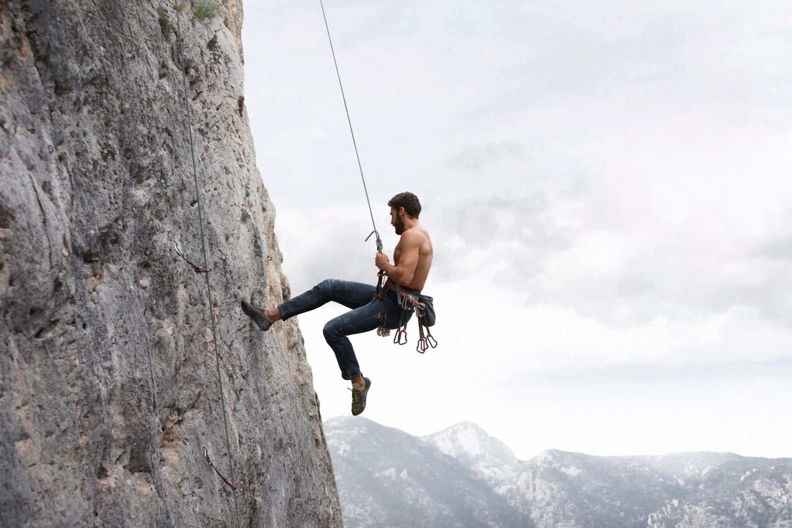 strong man climbing mountain with safety equipment scaled